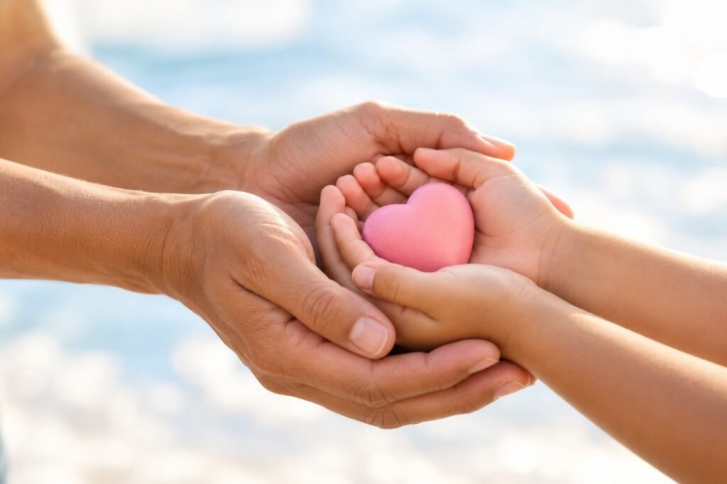 An adult and child gently holding a pink heart together